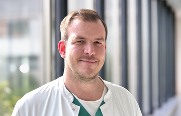 Nick Fröhlke im weißen Kittel in einem Flur des Krankenhauses Nick Fröhlke im weißen Kittel in einem Flur des Krankenhauses